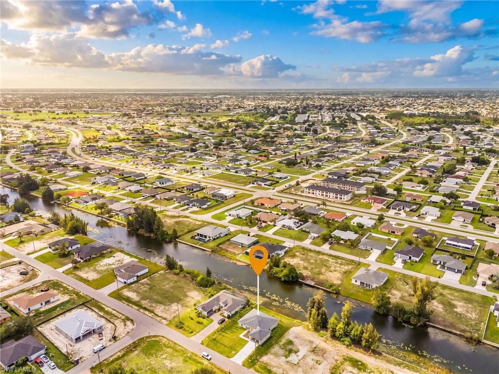 Aerial perspective showcasing a residential community with numerous single-story homes, a canal system, and undeveloped lots