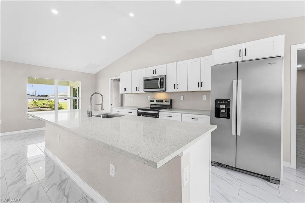 Open-concept kitchen featuring an expansive island with a stainless steel sink and gooseneck faucet