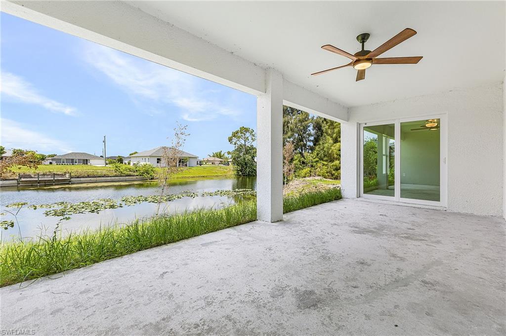 Expansive covered patio featuring a wood-finish ceiling fan with integrated lighting, concrete flooring, and sliding glass doors