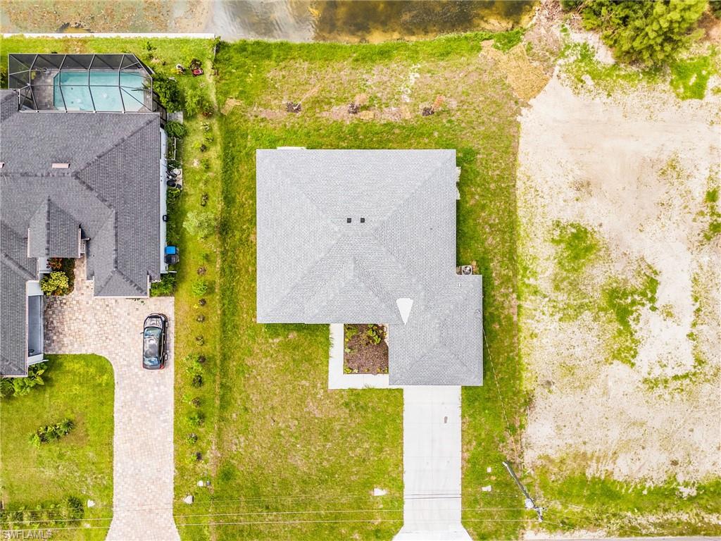 New construction residence with a gray shingle roof, concrete driveway, and established front landscaping