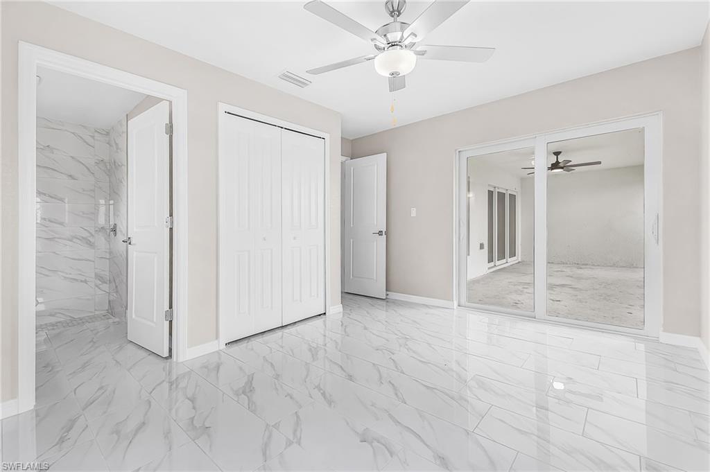 Spacious room featuring large format marble-look tile flooring, a contemporary ceiling fan with integrated lighting, and white bi-fold closet doors