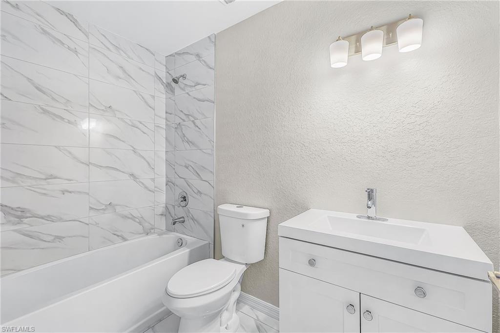 Bathroom featuring a white vanity with integrated sink, white cabinetry, and brushed nickel hardware