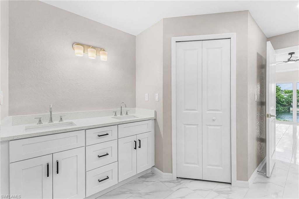 Dual vanity featuring white shaker-style cabinetry, quartz countertops, and brushed nickel fixtures
