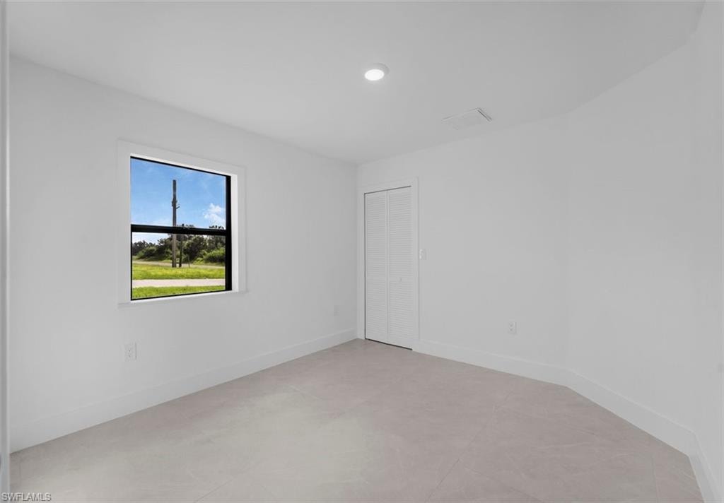 Room featuring light-toned flooring, white walls, and a single window with a black frame