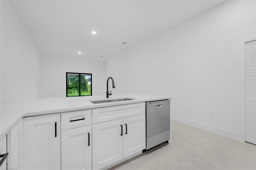 Kitchen island featuring white cabinetry, a stainless steel sink, and a matte black faucet