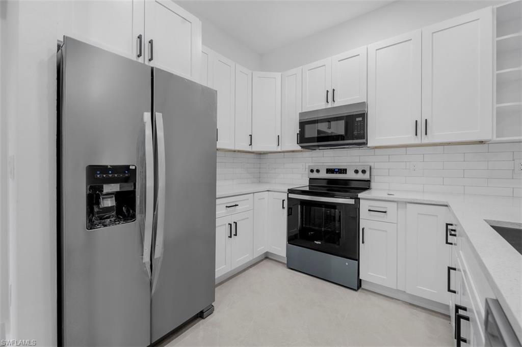 Modern kitchen featuring white shaker-style cabinetry with matte black hardware, stainless steel appliances, white subway tile backsplash, and light-toned countertops