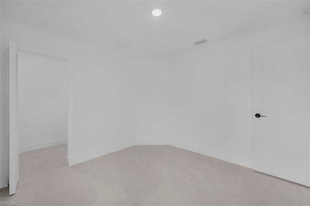Neutral white walls with recessed lighting and light-toned tile flooring