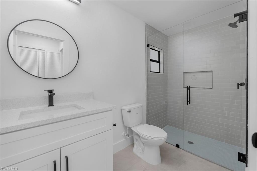 Modern bathroom featuring a frameless glass shower enclosure with subway tile surround, a built-in shower niche, and a matte black shower head