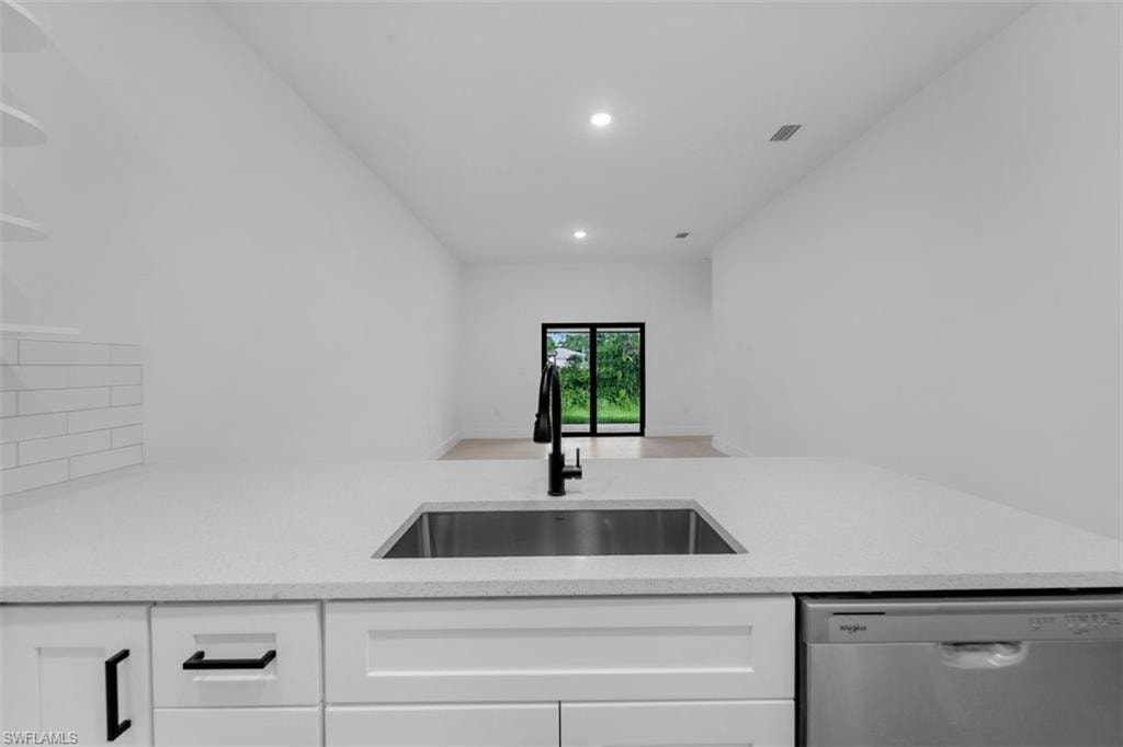 Modern kitchen island featuring a stainless steel undermount sink, matte black faucet, and white countertop
