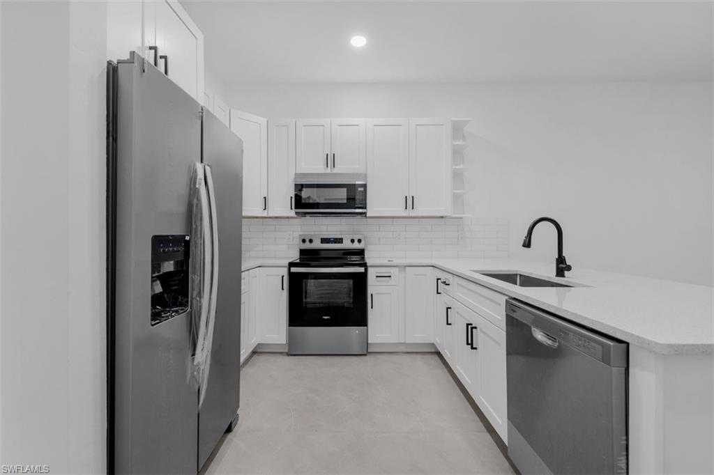 Contemporary kitchen featuring white cabinetry, stainless steel appliances, light-toned countertops, and a subway tile backsplash