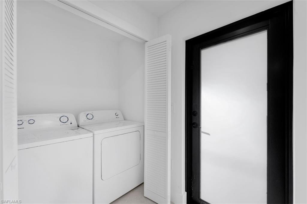 Dedicated laundry closet featuring a built-in washer and dryer set, bi-fold louvered doors, and a frosted glass door with a dark frame