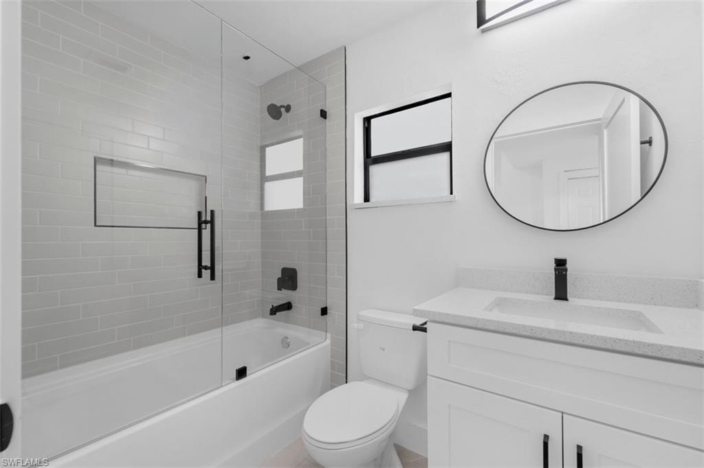 Bathroom featuring a tub/shower combination with glass enclosure, subway tile surround, and built-in niche