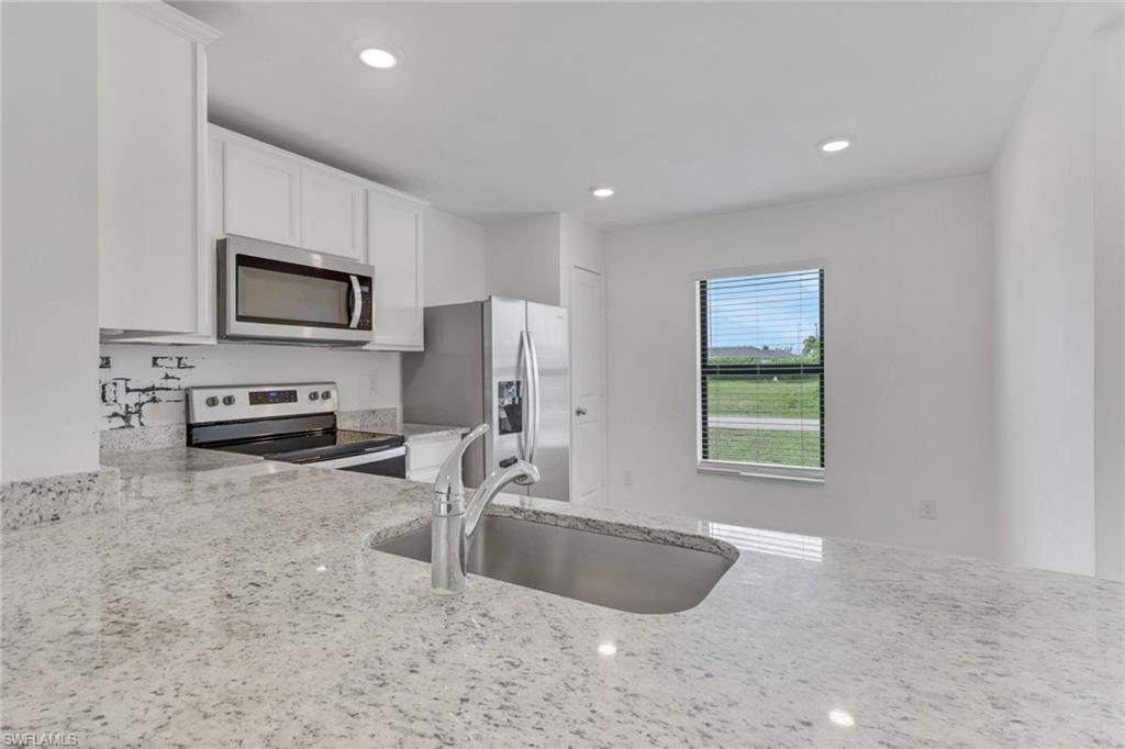 Open Kitchen with granite counter tops, white cabinets, very open and room for a table.