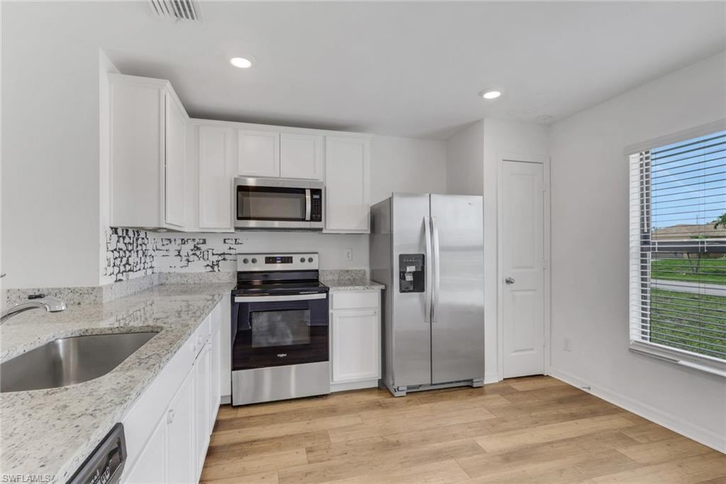 Open Kitchen with granite counter tops, white cabinets, very open and room for a table.