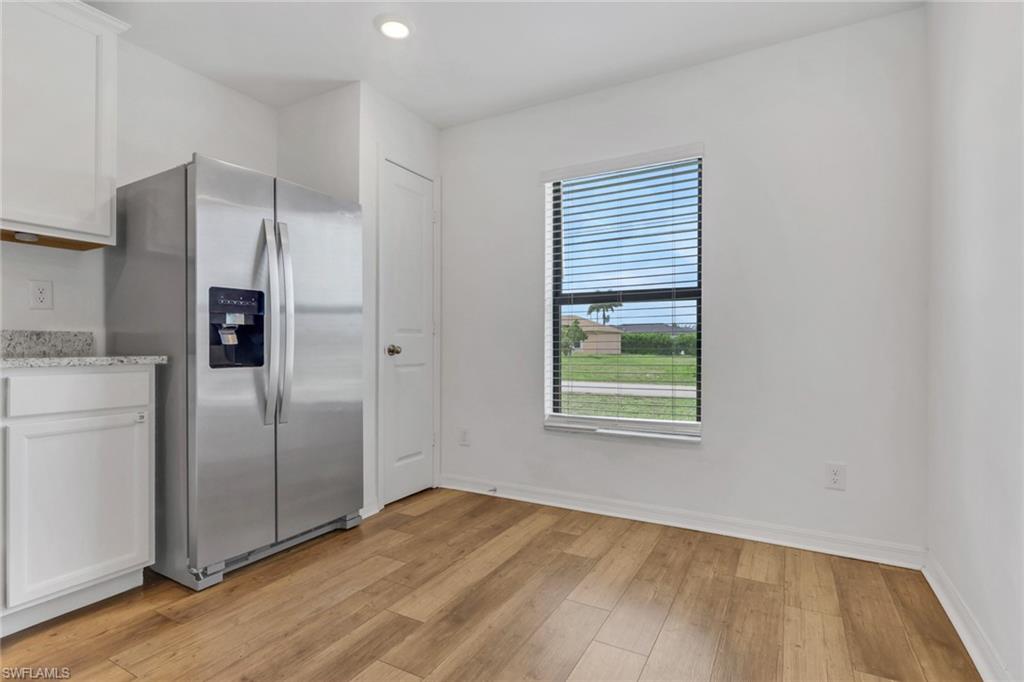Open Kitchen with granite counter tops, white cabinets, very open and room for a table.