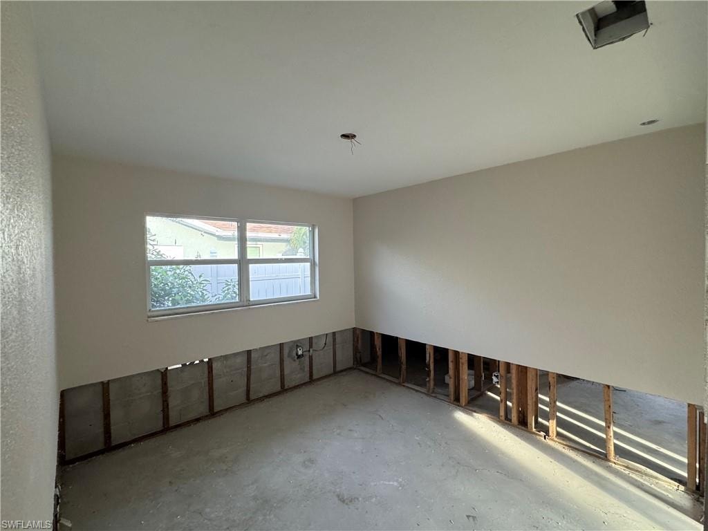 Interior space featuring a window, smooth ceiling with a recessed light fixture, and visible wall framing