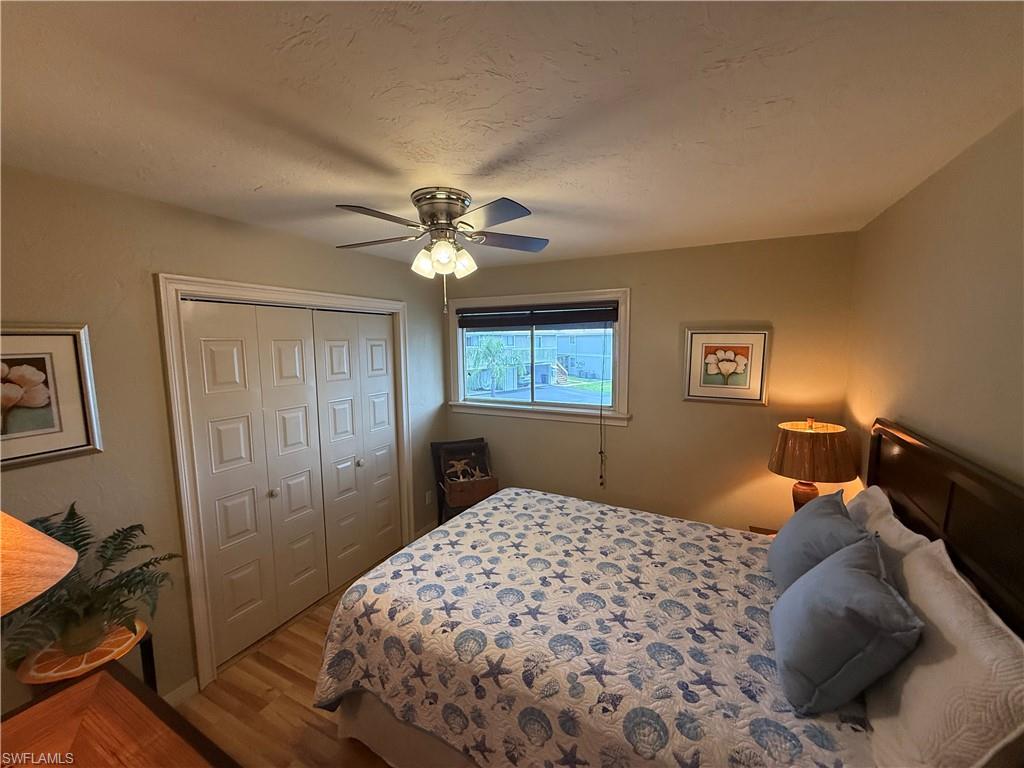 Bedroom featuring wood-finish flooring, a window with blinds, and a ceiling fan with integrated lighting