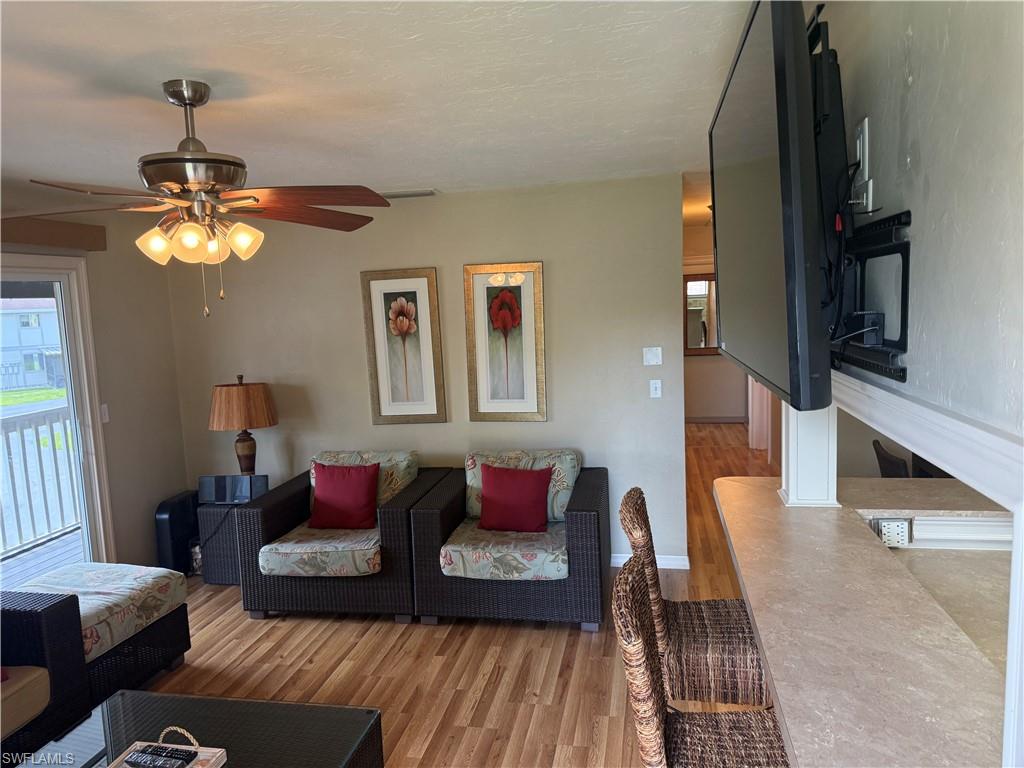 Living space featuring wood-finish flooring and a ceiling fan with integrated lighting