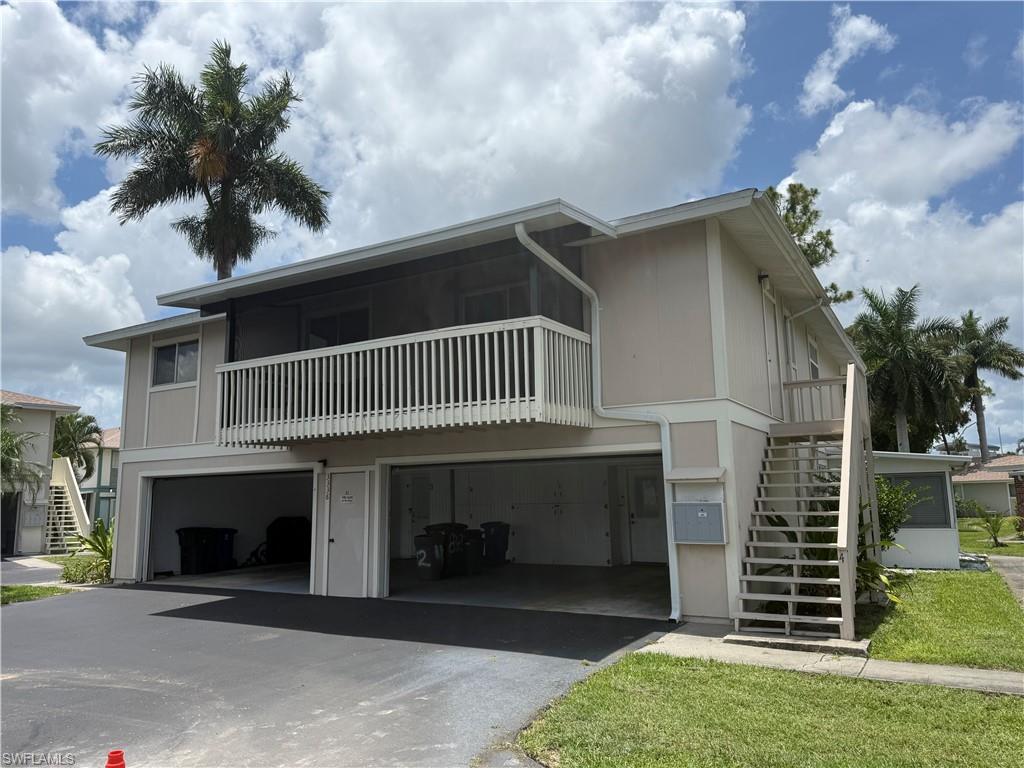 Two-story structure with two open garage bays, a screened upper balcony, and exterior stairs