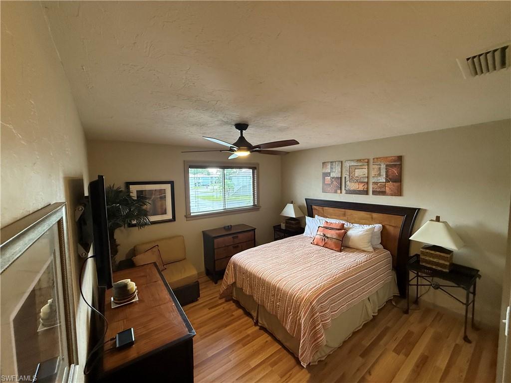 Bedroom featuring wood-finish flooring, a ceiling fan with integrated lighting, and a single window with blinds