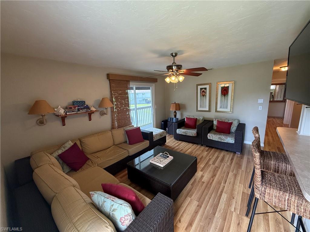 Spacious living area featuring wood-finish flooring, a ceiling fan, and sliding glass doors