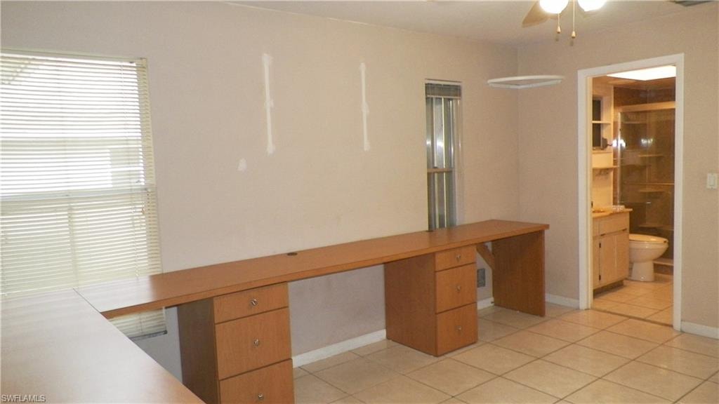 Room featuring tile flooring and built-in wood-finish desks with drawer storage