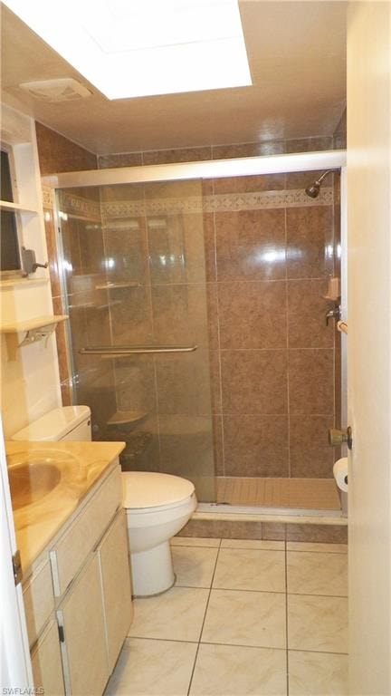 Bathroom featuring a glass-enclosed shower, integrated vanity with a single sink, tiled flooring, and a ceiling-mounted light fixture
