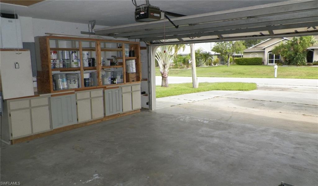 Garage interior featuring built-in wood cabinetry with open shelving and closed storage, a concrete floor, and a roll-up garage door mechanism