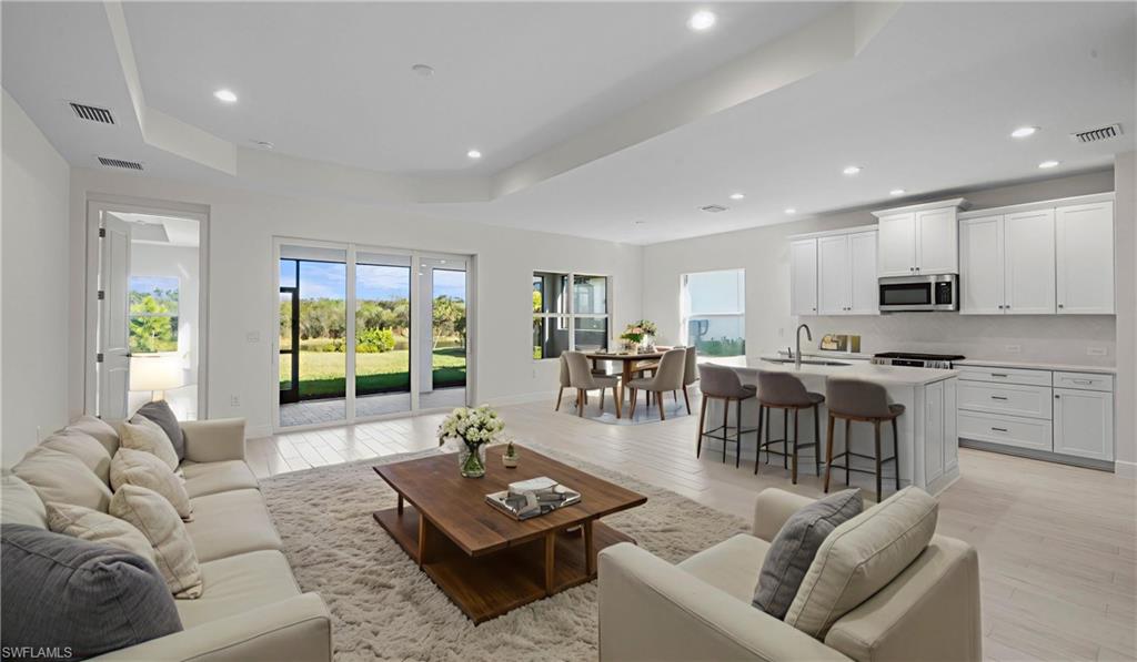 The heart of the home features soaring recessed ceilings, expansive living spaces, and seamless flow between the great room, dining area, and kitchen. Walls of glass frame peaceful preserve views while filling the home with natural light, creating an inviting atmosphere that feels both spacious and comfortable.