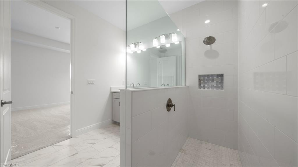 Spacious bathroom featuring a glass-enclosed shower with a rainfall showerhead and a mosaic tile niche