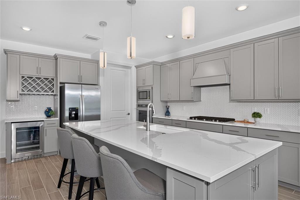 Dynamic kitchen with quartz countertops, gas cooktop, wine storage and abundant cabinetry with a large walk in pantry