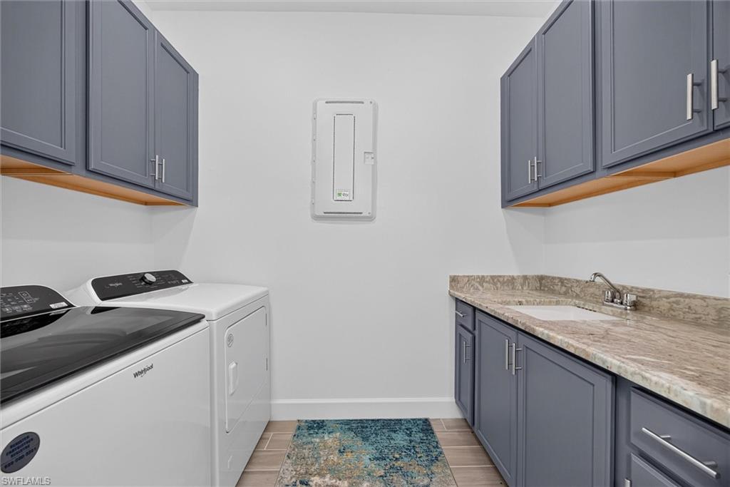 Well appointed laundry room featuring built in storage, and a convenient sink with extensive counter space