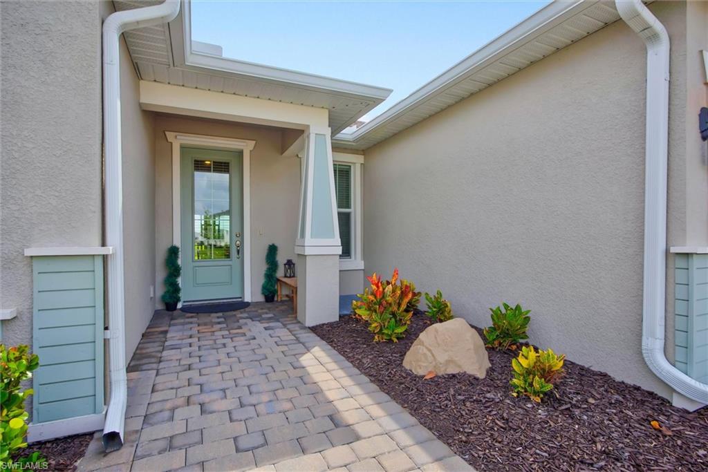 Inviting paver walkway leads toa  covered entry with decorative glass front door