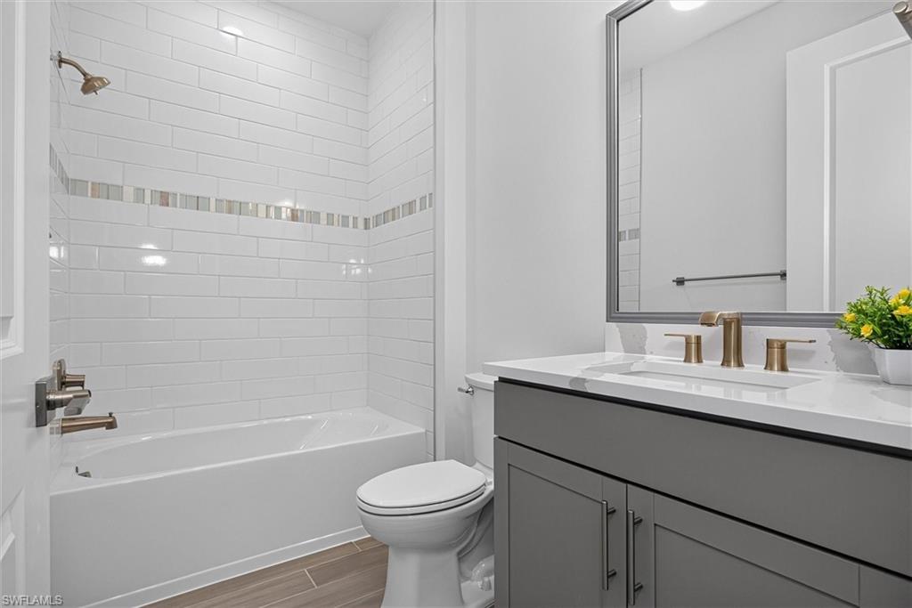 Bright guest bath showcasing surfaces and a sleek tiled shower/tub combination   Tile to the ceiling for that elegant look