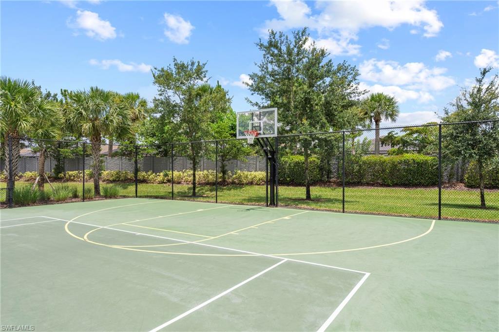 Outdoor basketball court featuring a clear backboard and a black chain-link fence perimeter