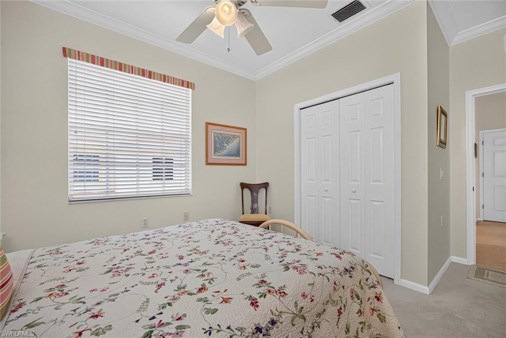 Bedroom featuring a window with horizontal blinds, bi-fold closet doors, a ceiling fan with integrated lighting, crown molding, and carpet flooring