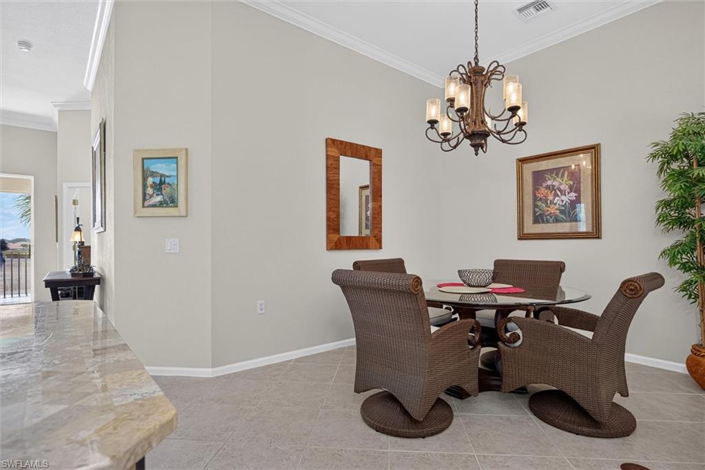 Dining area featuring a decorative chandelier with frosted glass shades, crown molding, and neutral wall paint