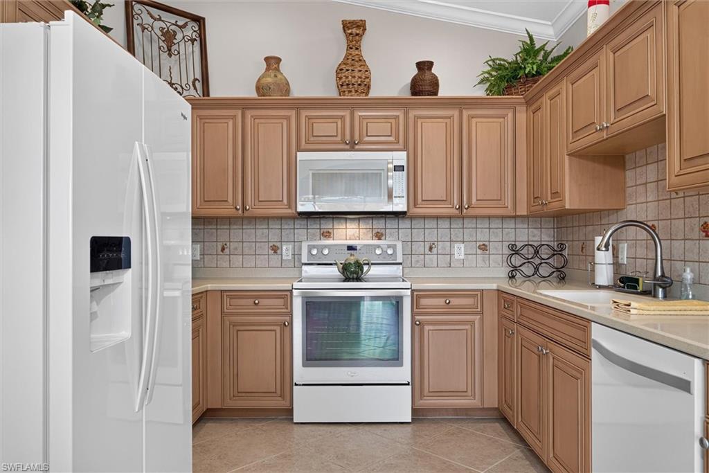 Kitchen featuring wood-finish cabinetry, white appliances, and a tiled backsplash