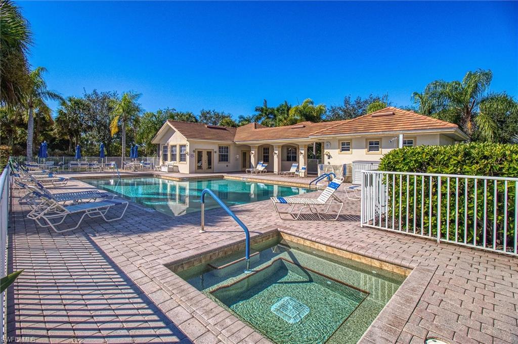 Resort-style pool area featuring a rectangular swimming pool, a separate square spa, and extensive paver decking