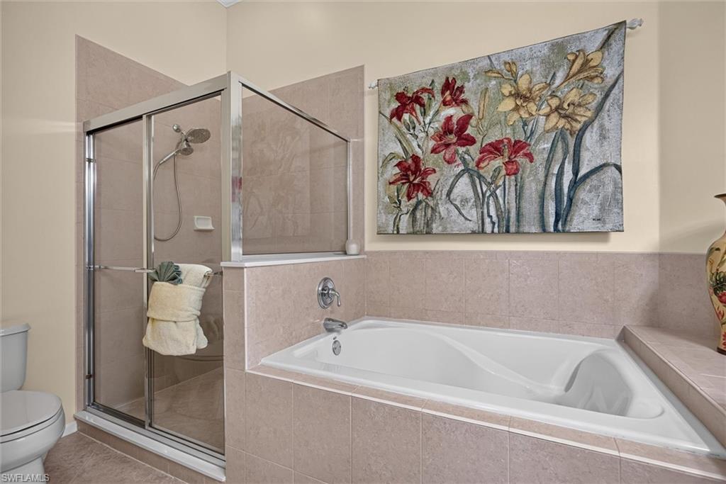 Tiled bathroom featuring a built-in soaking tub and a glass-enclosed shower with a handheld showerhead