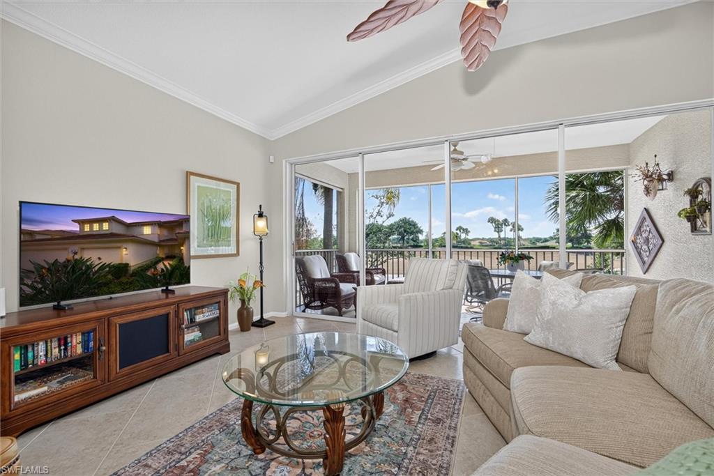 Spacious living area featuring neutral wall tones, tile flooring, and vaulted ceilings with crown molding