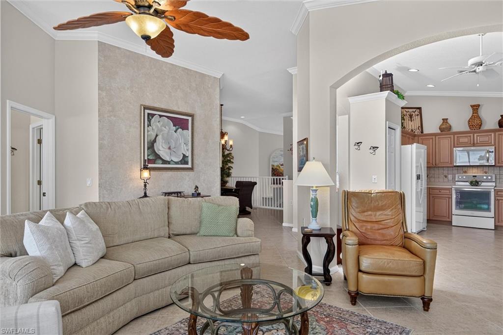 Living area featuring vaulted ceilings, a decorative textured accent wall, and a tropical-style ceiling fan