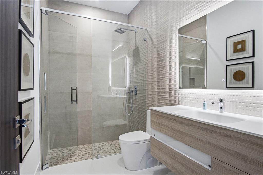 Walk-in shower with clear glass enclosure, pebble-style flooring, and integrated bench seating