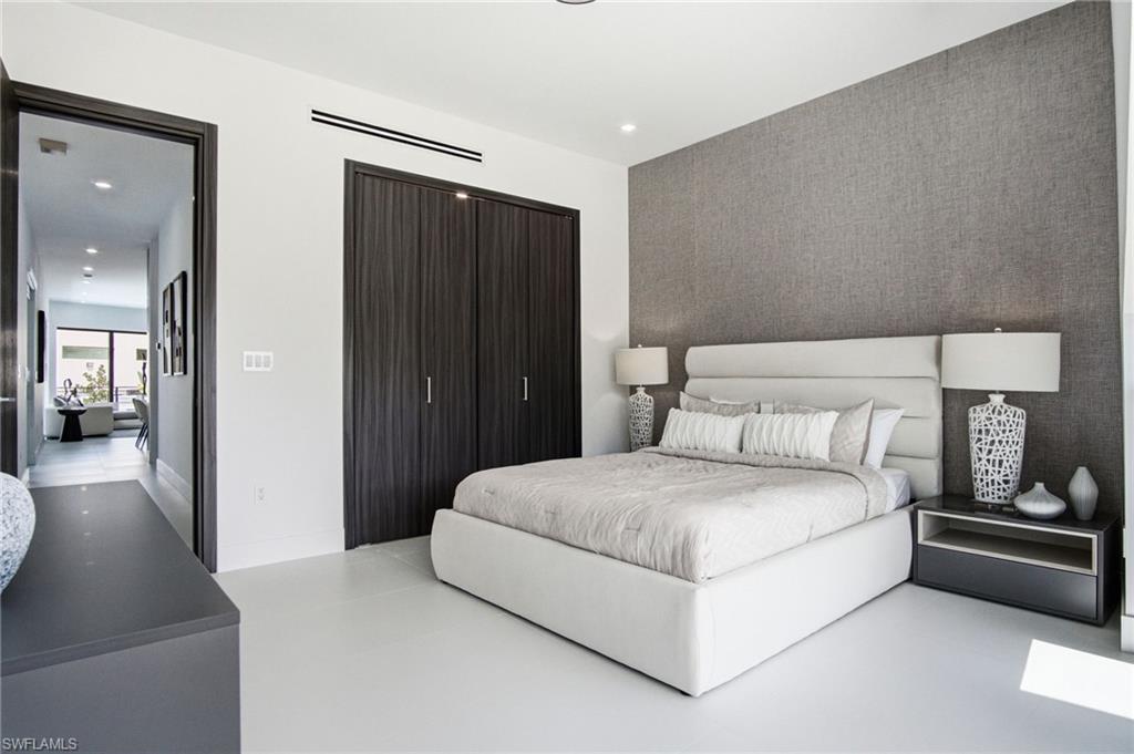 Bedroom featuring a textured accent wall, dark wood-finish bi-fold closet doors, recessed lighting, and light-toned flooring