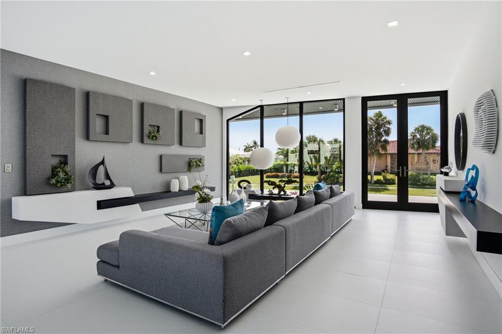 Spacious living area featuring large format light-toned flooring, expansive glass doors, recessed lighting, and a contemporary built-in wall unit