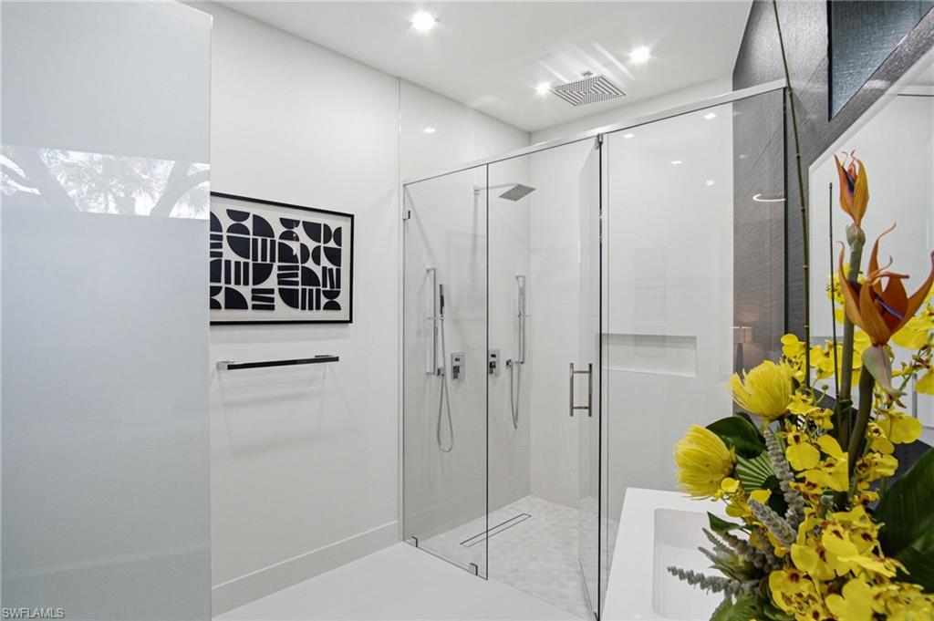Modern bathroom featuring a frameless glass shower enclosure, a rainfall showerhead, and a recessed shower niche