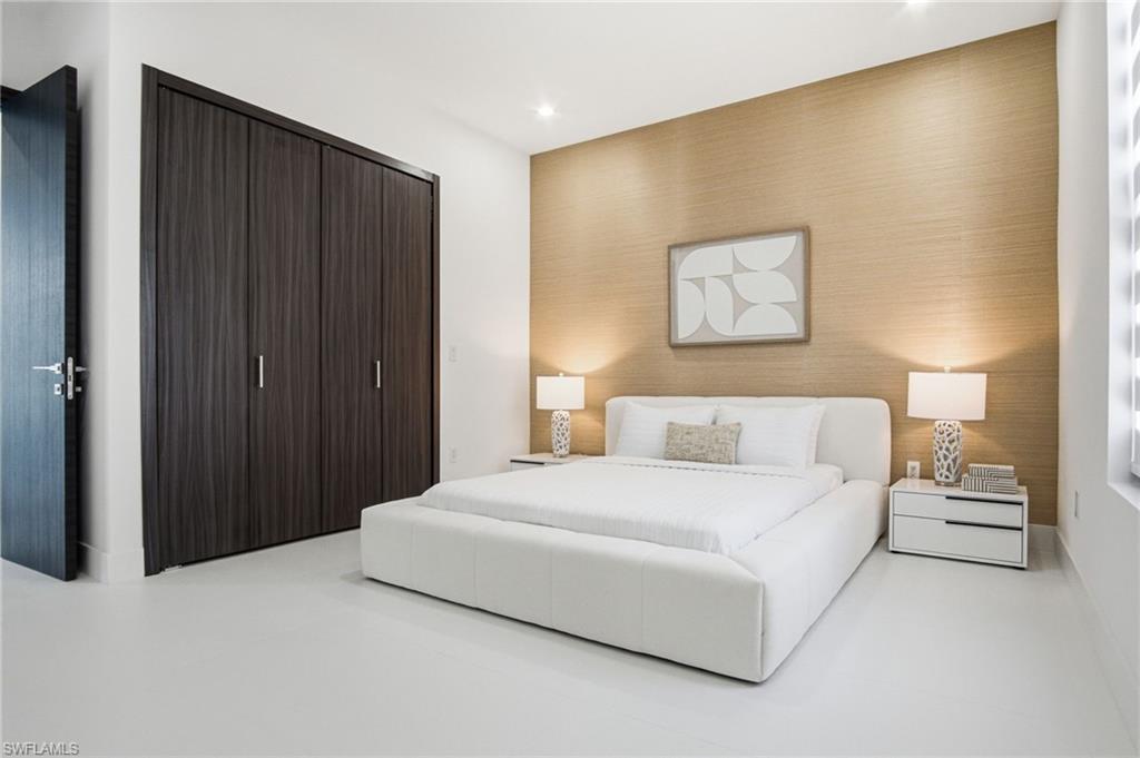 Contemporary bedroom featuring a textured accent wall, recessed lighting, and light-colored flooring