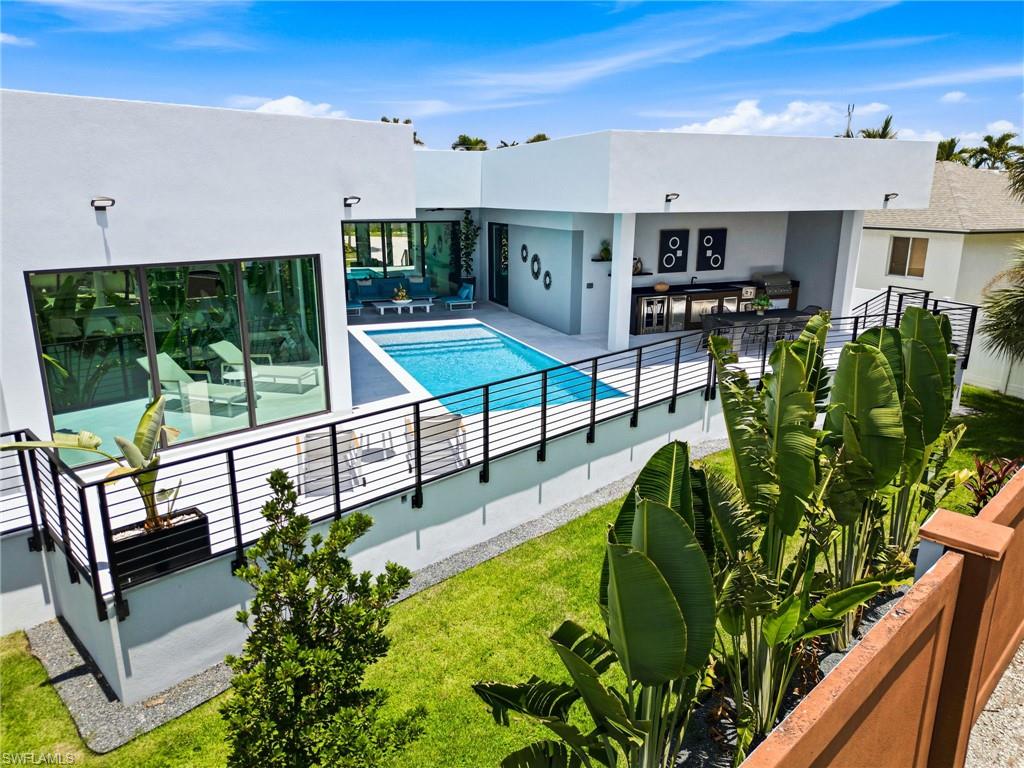 Modern exterior with expansive glass doors, a rectangular pool, and a structured outdoor kitchen