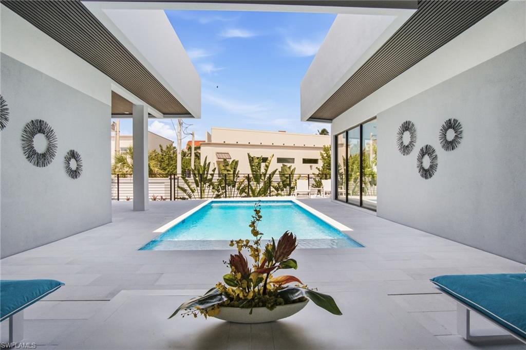 Outdoor patio featuring a rectangular swimming pool, light-toned patio flooring, and large sliding glass doors