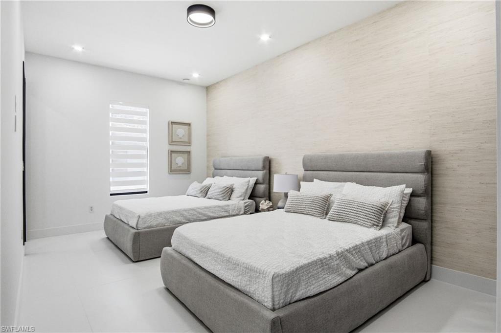 Bright bedroom featuring a textured accent wall and recessed lighting